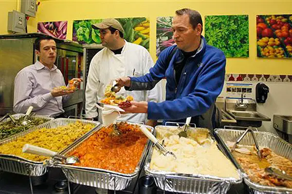 Photograph of  Great Performances catering captain Ken Bohlander, right, trying dishes that will be served on behalf of the Salvation Army on Thanksgiving Day by Kathy Willens/AP